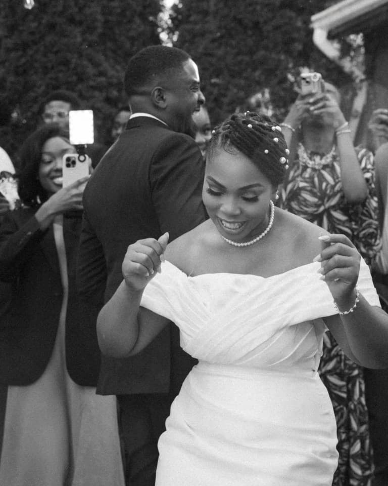Bride dancing at an outdoor reception as guests record with phones behind her