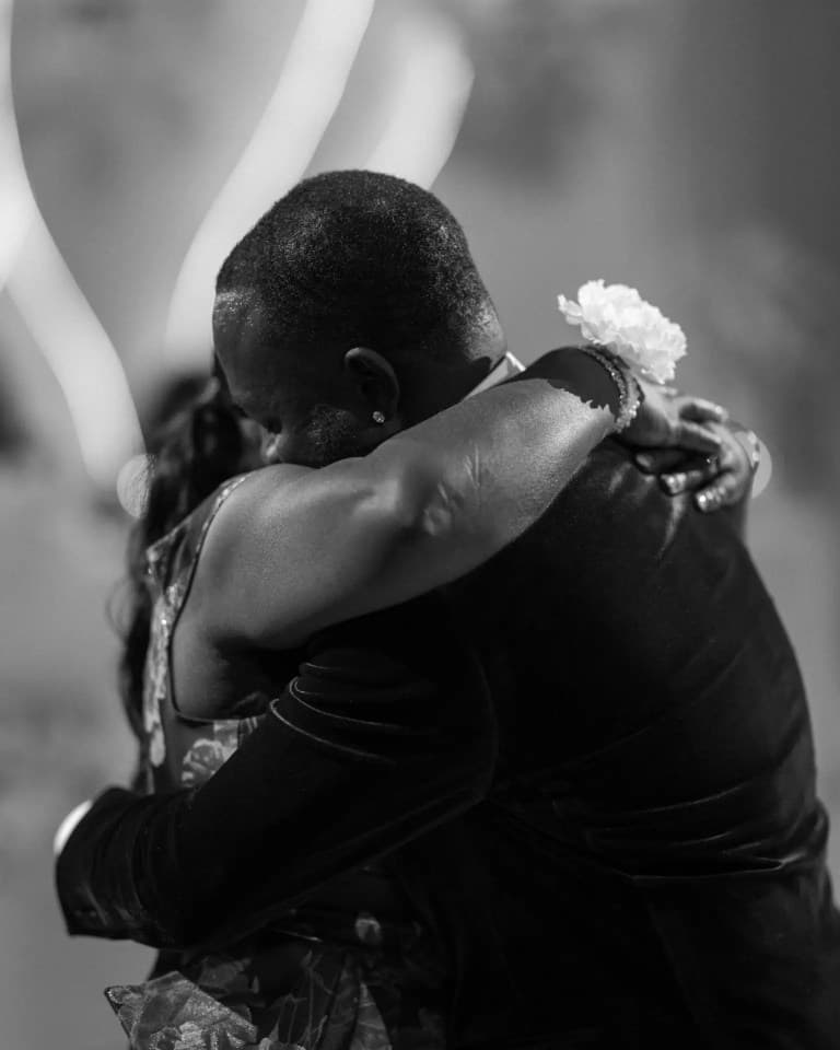 Couple in a close embrace while dancing, white flower and bracelet at the shoulder
