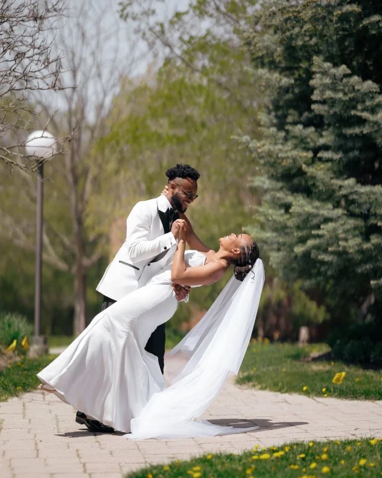 Groom in white dinner jacket dipping the bride on a paved garden path