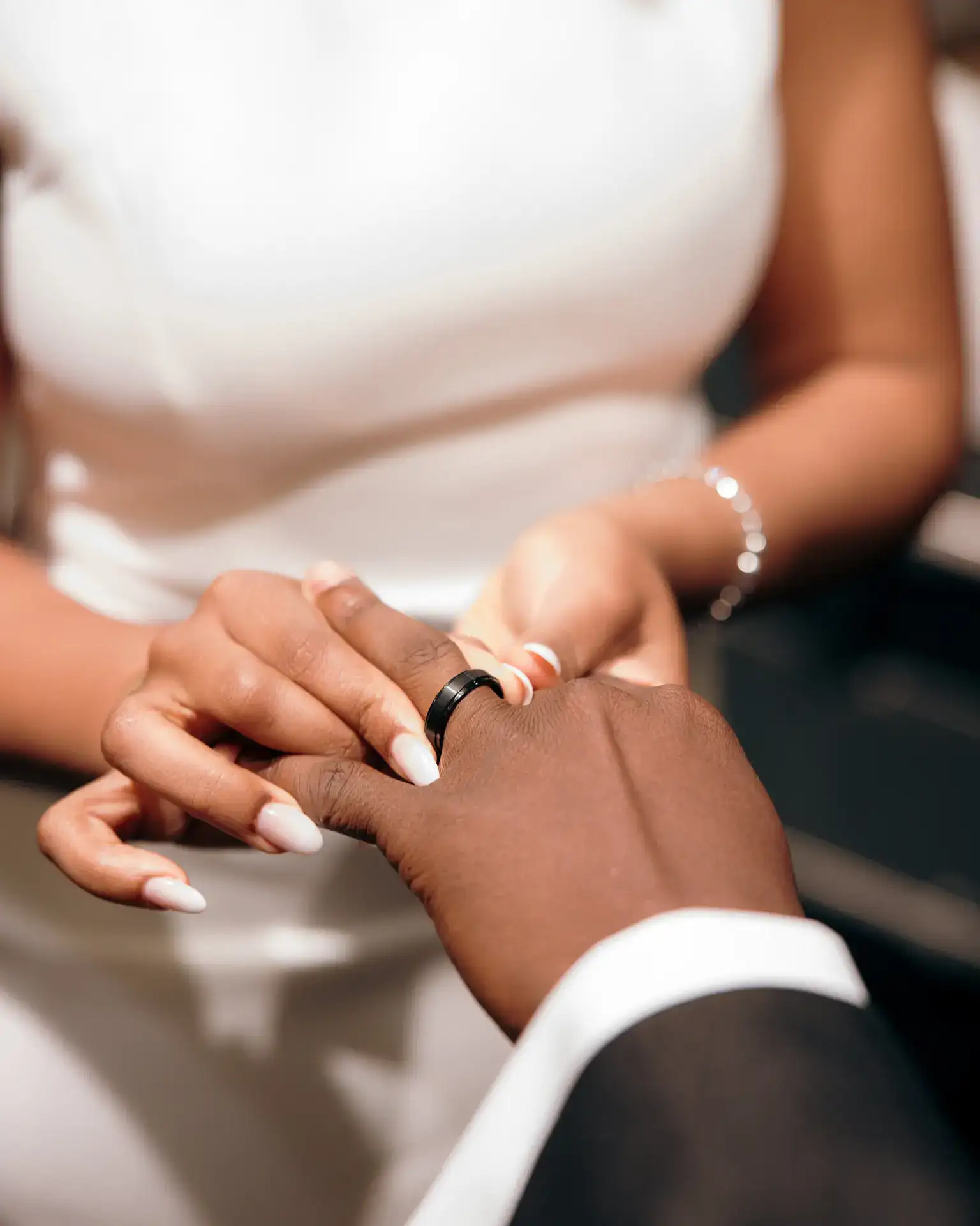 Bride sliding a black wedding band onto groom's finger during ring exchange