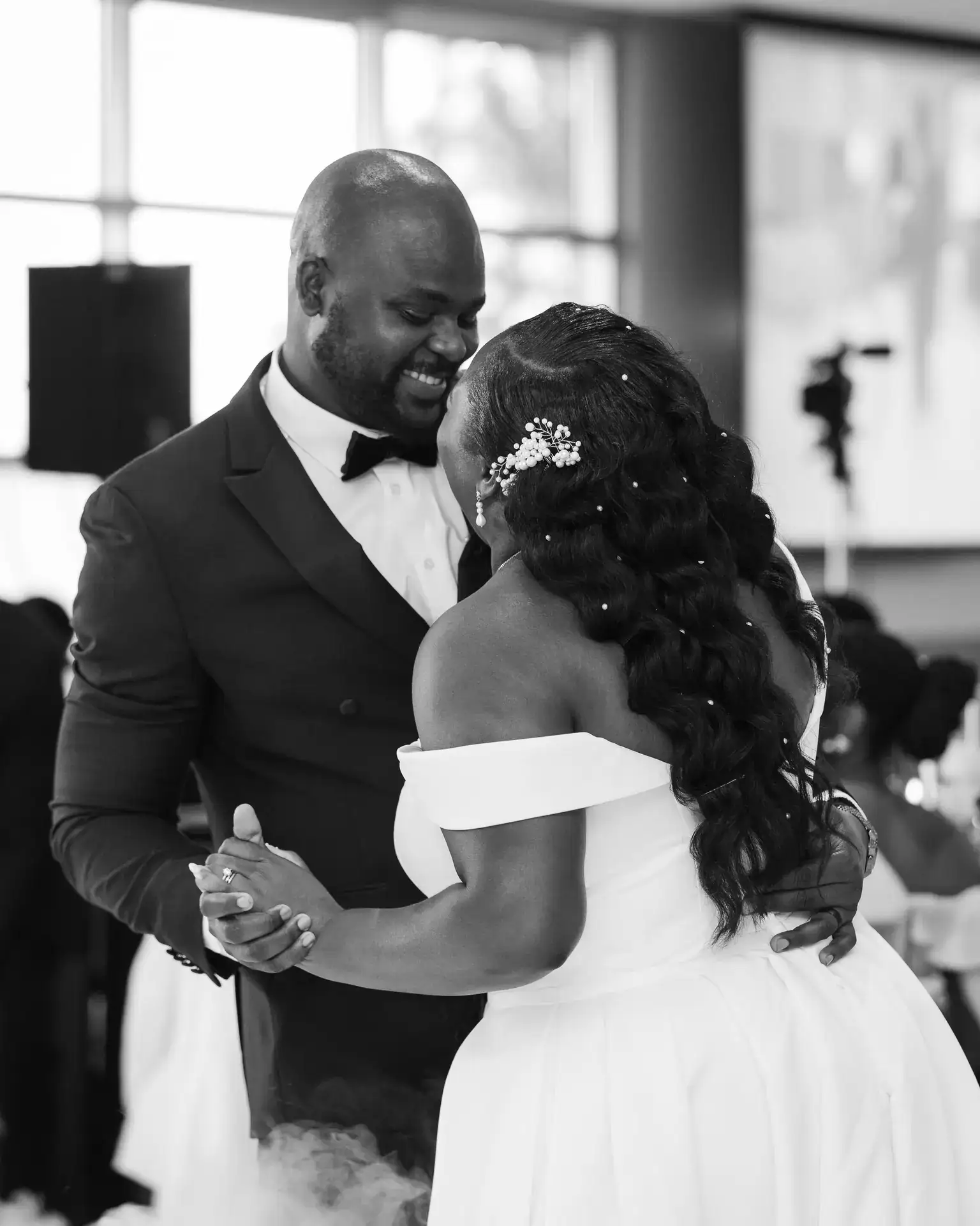 Bride and groom sharing a first dance with clasped hands amid low fog