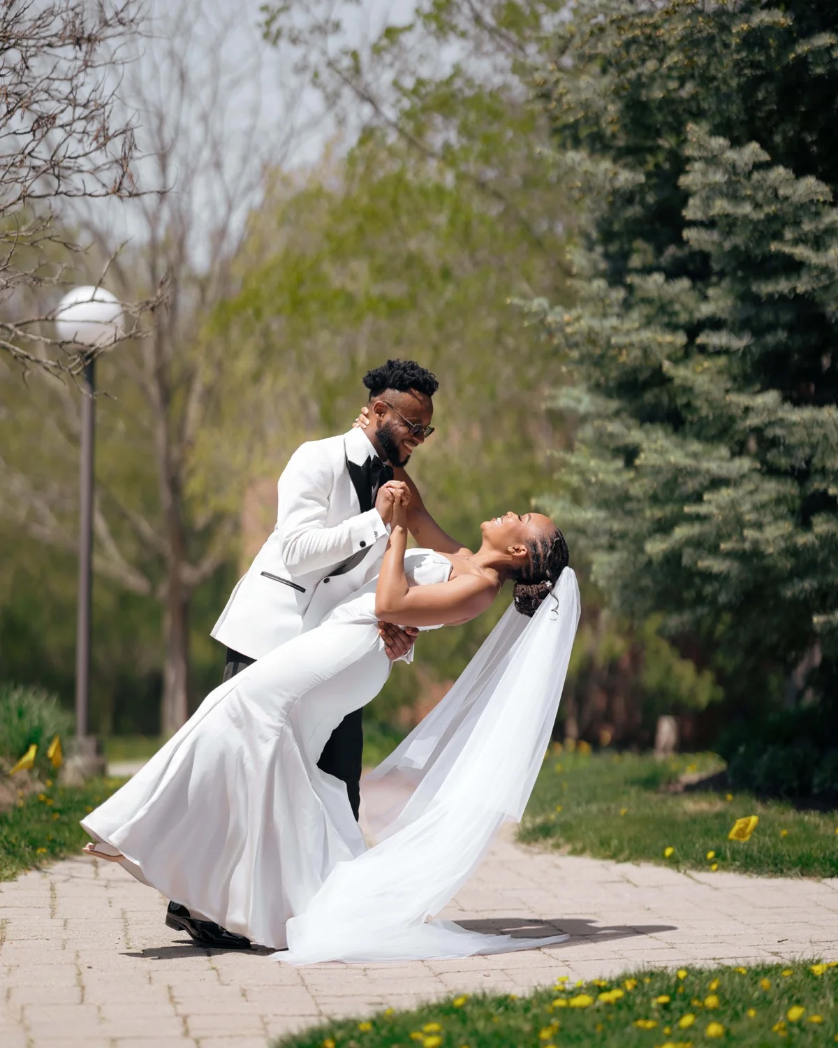 Groom in white tuxedo jacket dipping the bride on a garden path