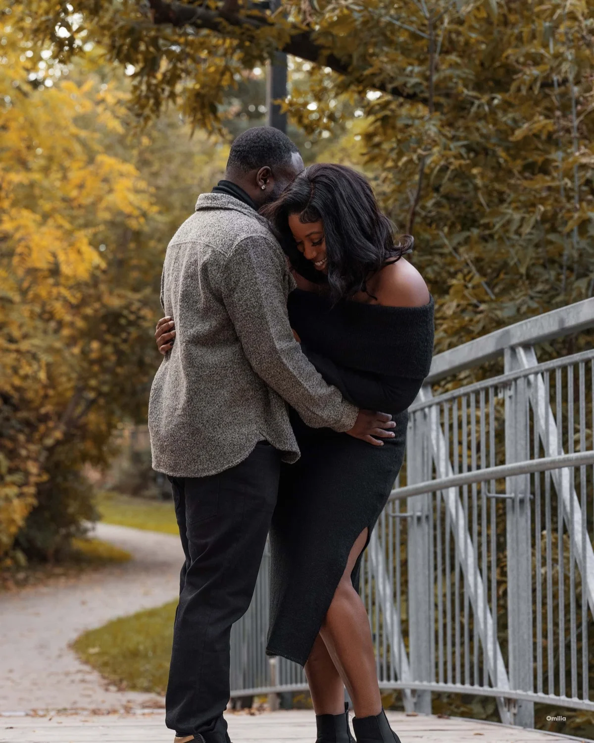 Couple embracing on a footbridge surrounded by golden autumn foliage
