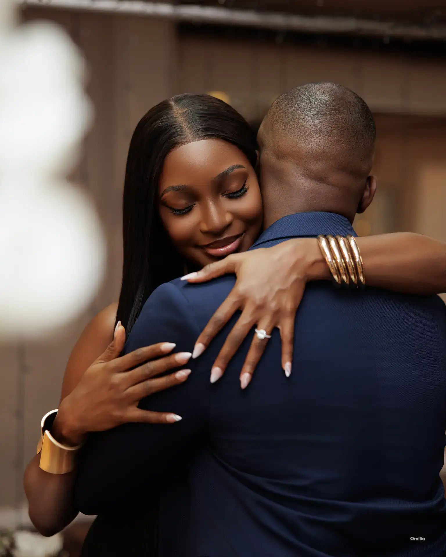 Woman embracing partner with diamond ring and gold bangles visible on her hands